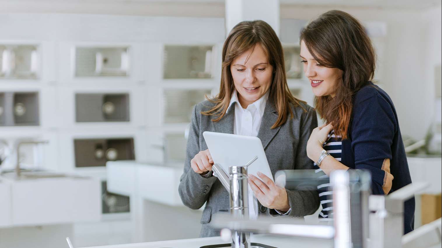 sales woman helping client in a kitchen retailer with a 3D planning solution on a tablet