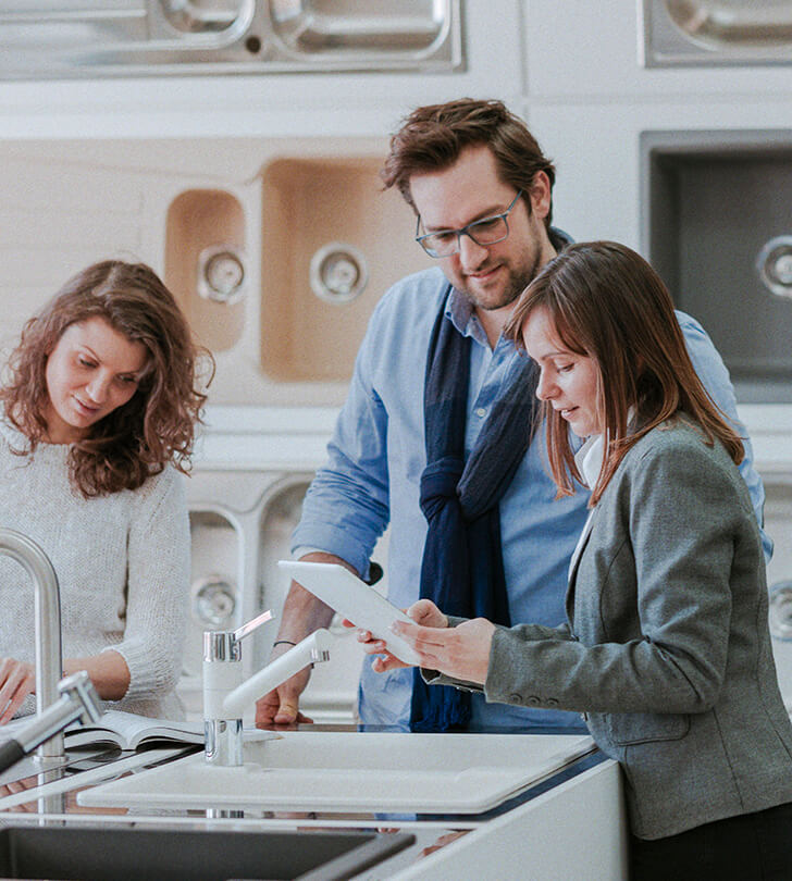 saleswoman with tablet consulting couple in a kitchen and bath store