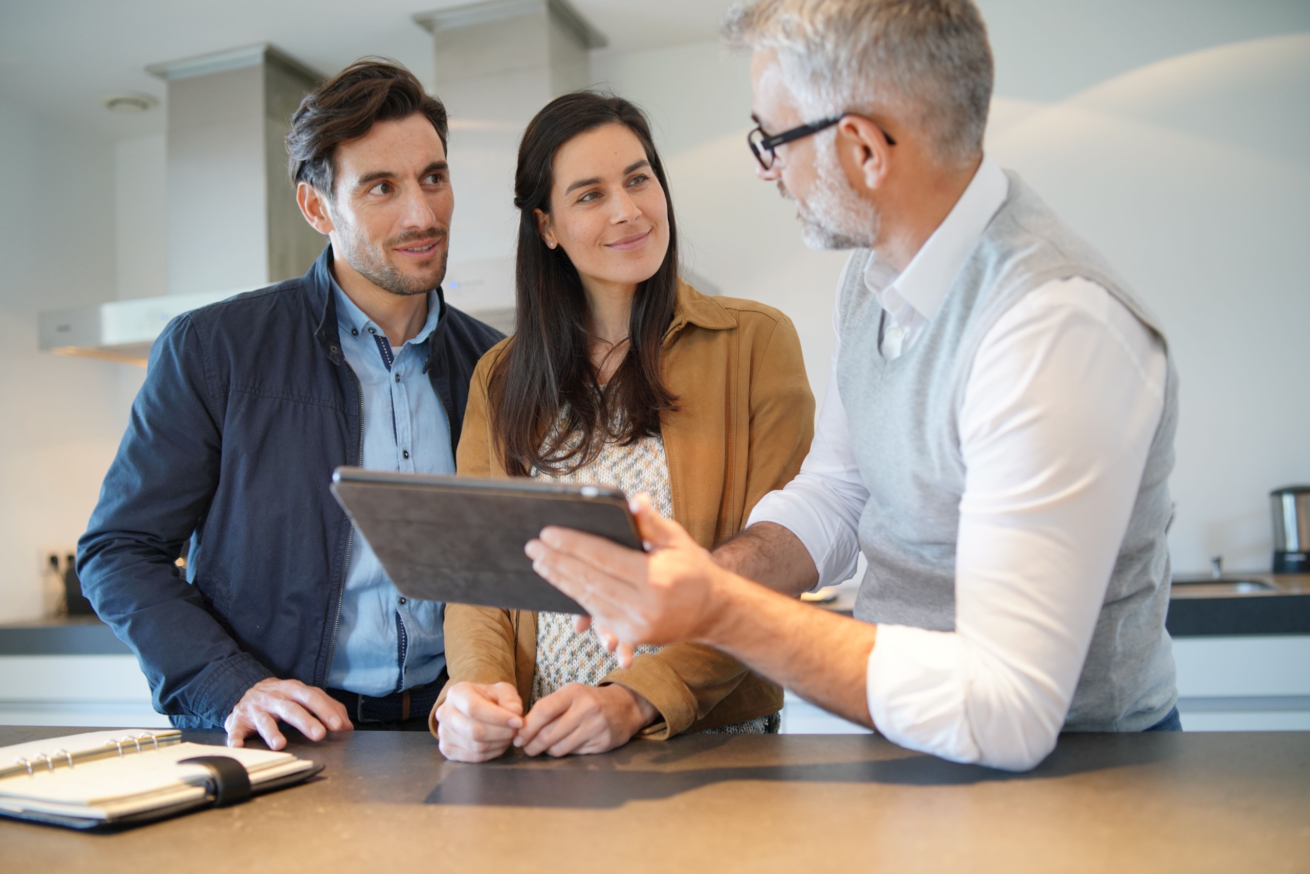 man explaining 3d planning with tablet to young couple