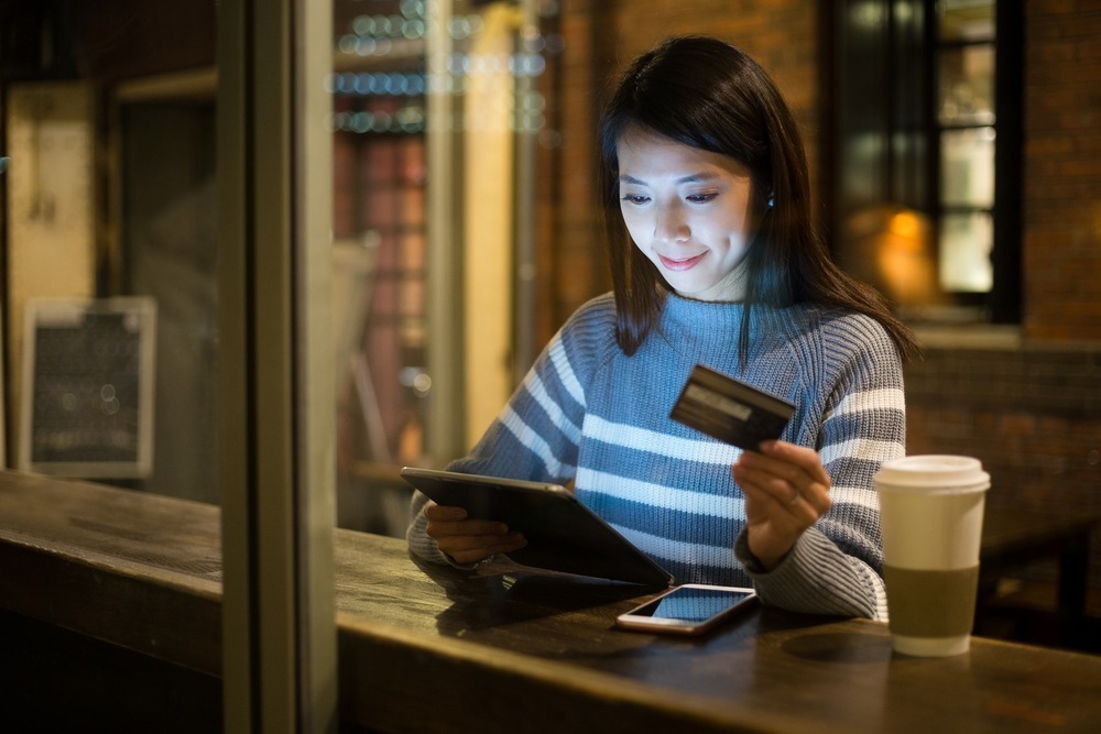 young woman paying with credit card online in a cafe