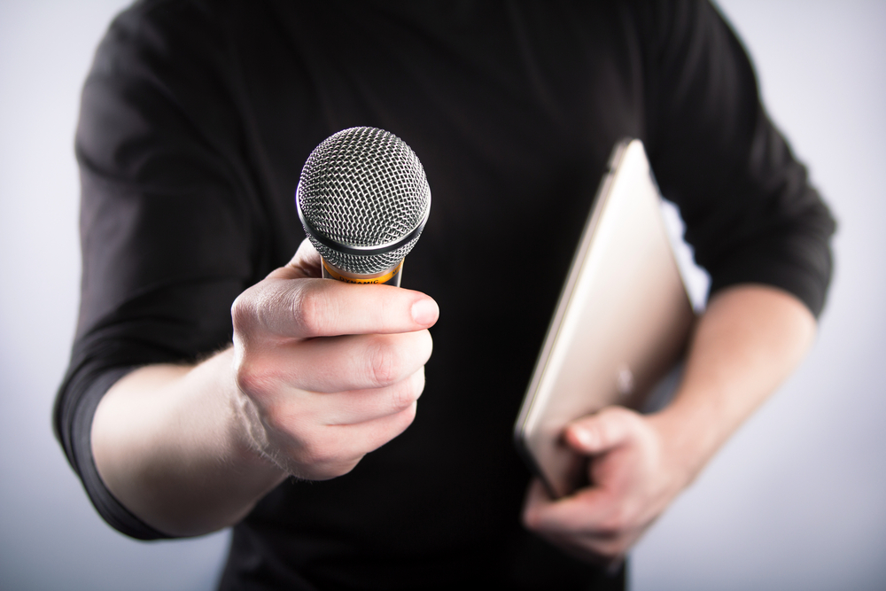 man holding a microphone and notebook